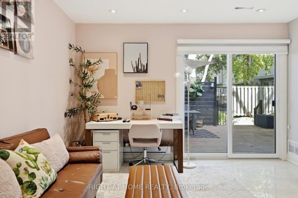 Den with desk, sofa, and sliding glass doors opening to a backyard deck. - 45 - 4101 Westminster Place, Mississauga