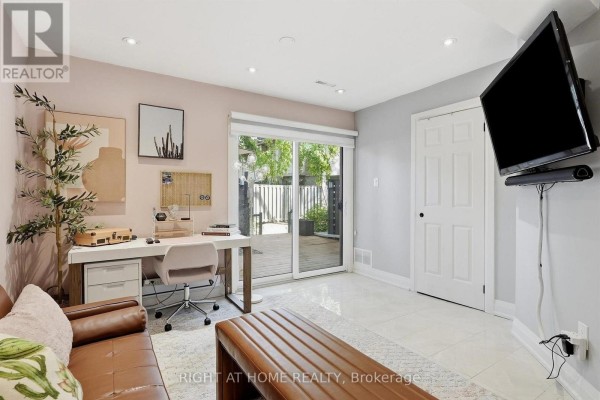 Den with desk, sofa, television mounted on wall, and sliding glass doors to backyard. - 45 - 4101 Westminster Place, Mississauga