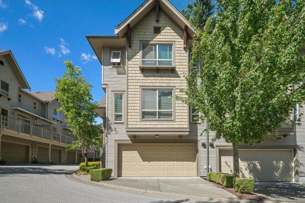 Exterior front view of a beige and grey townhouse with a beige garage door and green trees. - 45 2738 158 Street, Surrey