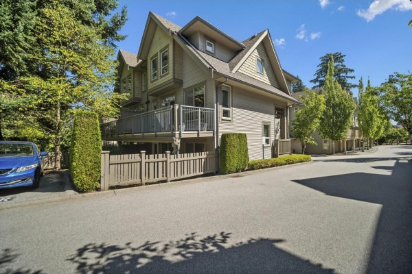Side view of a beige townhouse complex with multiple balconies and a wooden fence. - 45 2738 158 Street, Surrey