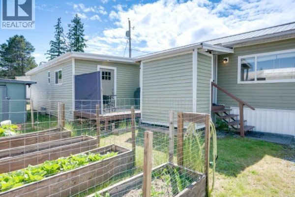 Bedroom with a king-size bed, headboard, and portable air conditioner. - 45-4500 Claridge Road, Powell River