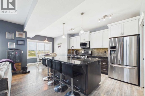 Kitchen with a large island, black granite counters, and stainless steel appliances. - 45 Alderwood Close, Blackfalds