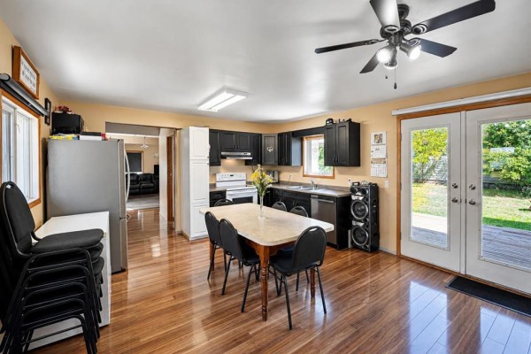 Kitchen and dining area with light laminate floors, black cabinets, white appliances, and dining table. - 45 Bredin Avenue, Rosenfeld