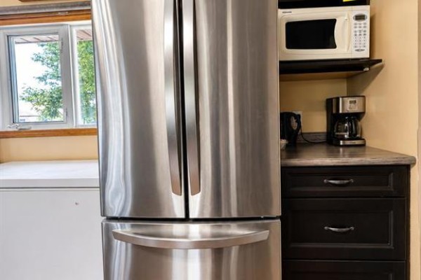 Stainless steel French door refrigerator with a white microwave on a shelf above. - 45 Bredin Avenue, Rosenfeld