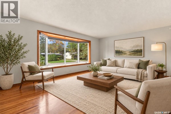 Living room with hardwood floors, a large bay window, and beige furniture. - 45 Cardinal Crescent, Regina