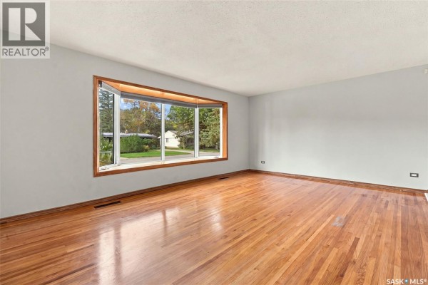 Living room with hardwood floors and a large bay window overlooking the front yard. - 45 Cardinal Crescent, Regina