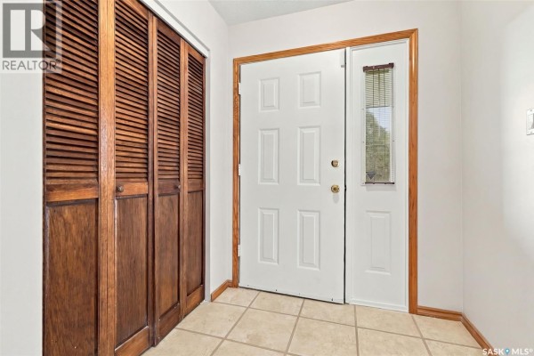 Interior front door with a wood-slatted closet and beige tiled floor. - 45 Cardinal Crescent, Regina