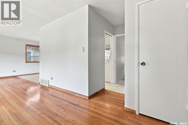 Interior hallway with hardwood floors, grey walls, and doors to other rooms. - 45 Cardinal Crescent, Regina