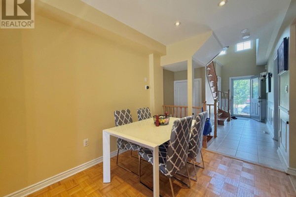 Dining area with a white rectangular table, grey patterned chairs, and a view of the hallway and stairs. - 45 Carrillo Street, Vaughan