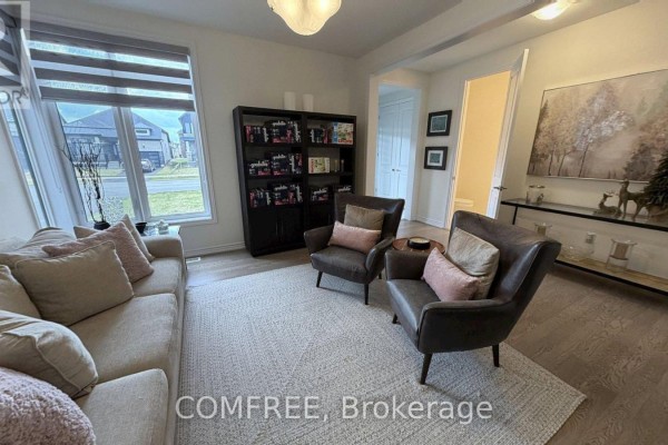 Living room with sofa, armchairs, bookcase, and view of windows and hallway. - 45 Del Ray Crescent, Wasaga Beach