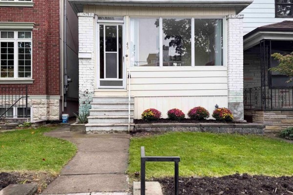 Sunroom with brown sofa, tile floor, and large windows overlooking the street. - 45 Eaton Avenue, Toronto