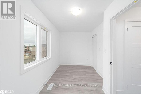 Interior room with white walls, light wood laminate flooring, and a large window. - 45 Hay Lane, Barrie
