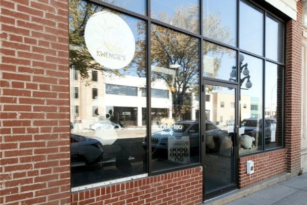 Close-up of storefront window with "Kwencie's" logo and bubble tea sign inside. - 45 High Street W, Moose Jaw