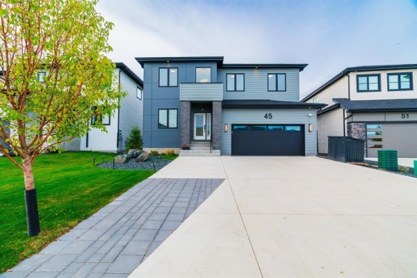 Exterior of a modern grey and blue two-story home with a paved driveway and walkway. - 45 Karschuk Bay, Winnipeg
