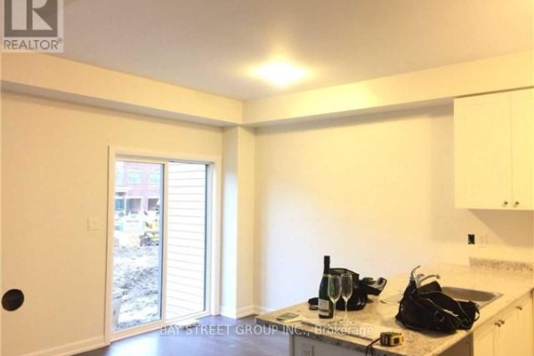 Interior view of a bright room with white walls, a sliding glass door, and granite countertops. - 45 Longshore Way, Whitby