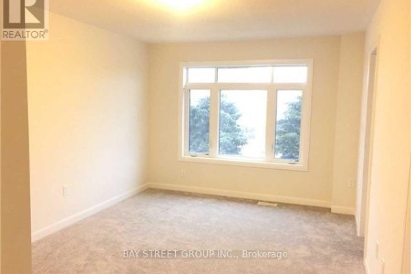 Interior view of an empty room with beige walls, plush carpeting, and a large white-framed window. - 45 Longshore Way, Whitby
