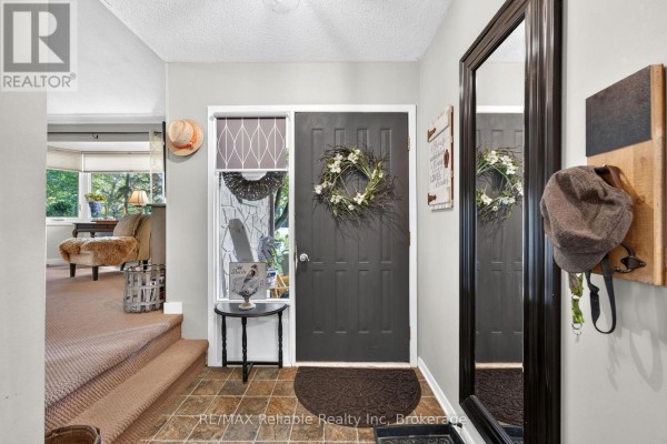 Interior entryway with dark gray front door, decorative wreath, and a large mirror. - 45 Main Street S, Bluewater