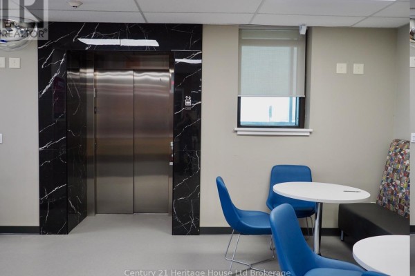 Elevator bank with polished black marble-style surround and adjacent window with blinds. - 45 Metcalf Street, Woodstock
