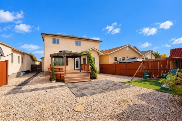 Backyard view with a wooden deck, a pergola, gravel landscaping, and a swing set. - 45 Moldan Bay, Winnipeg