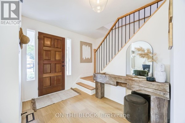 Foyer entrance with wood flooring, a console table, mirror, and a view of the living room. - 45 Palmwood Gate, Whitchurch Stouffville