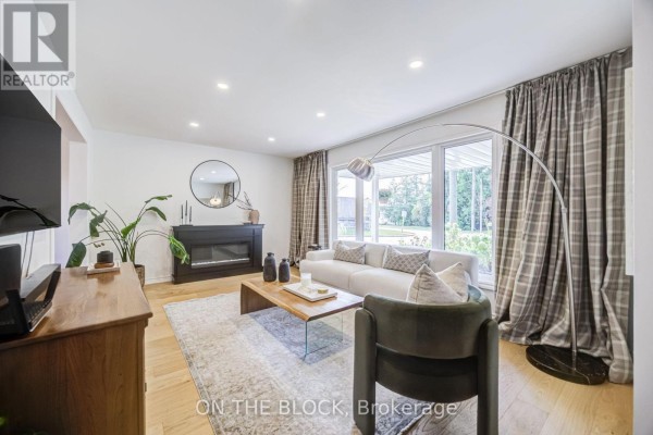 Living room with a fireplace, sofa, coffee table, large windows, and plaid curtains. - 45 Palmwood Gate, Whitchurch Stouffville