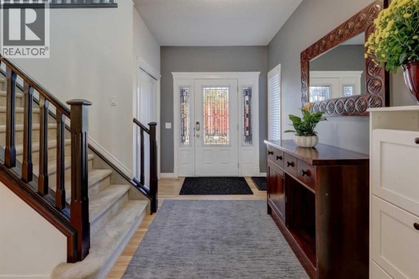 Foyer with a grey runner, dark wood staircase, glass-panelled front door, and a dark wood console table. - 45 Royal Oak Manor Nw, Calgary