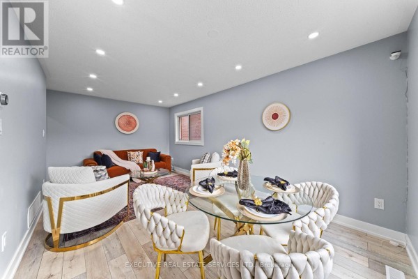Round glass dining table with white chairs and a sofa - 45 Sahara Trail Brampton