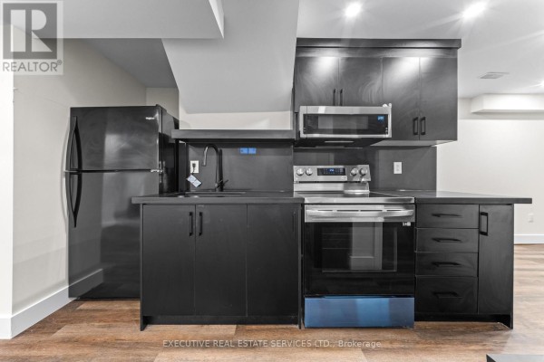 Modern kitchen with black appliances and cabinets - 45 Sahara Trail Brampton