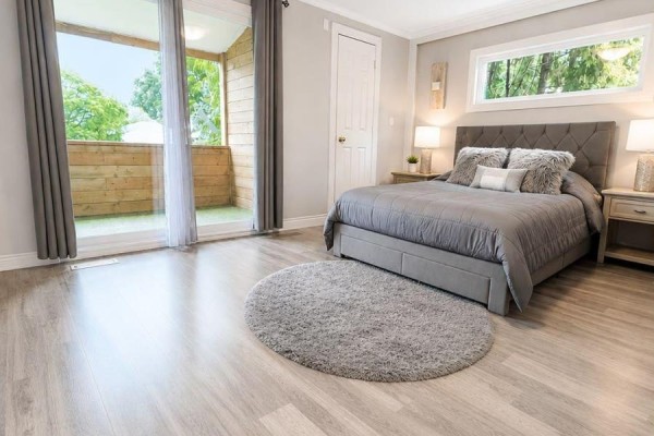 A bedroom featuring a gray tufted bed, light gray walls, and sliding glass doors to a balcony. - 45 Sandusky Crescent, Aurora