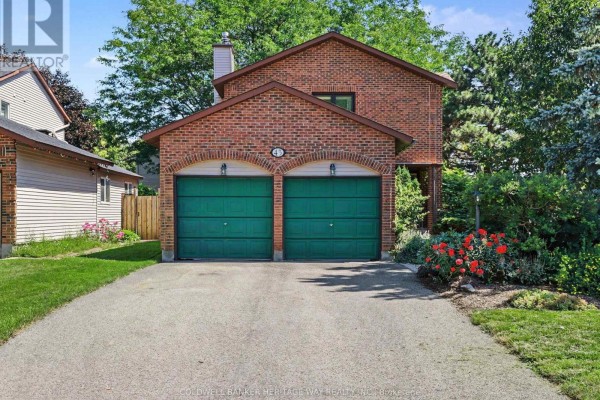 Brick house exterior with a double garage, green doors, stone walkway, and lush greenery. - 45 Shadetree Crescent, Ottawa