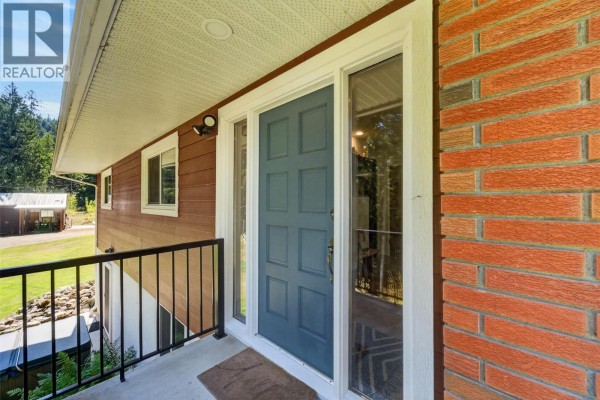 Close-up of the front entrance with a blue door, brick and wood siding. - 450 20 Avenue Sw, Salmon Arm