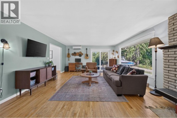 Living room with a large brown sofa, wooden coffee table, and a TV on a credenza. - 450 20 Avenue Sw, Salmon Arm