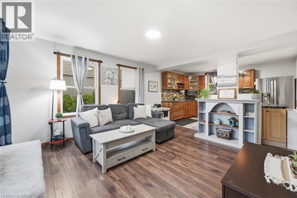 Living room with gray sectional sofa, coffee table, and open concept kitchen beyond. - 450 East 42nd Street, Hamilton