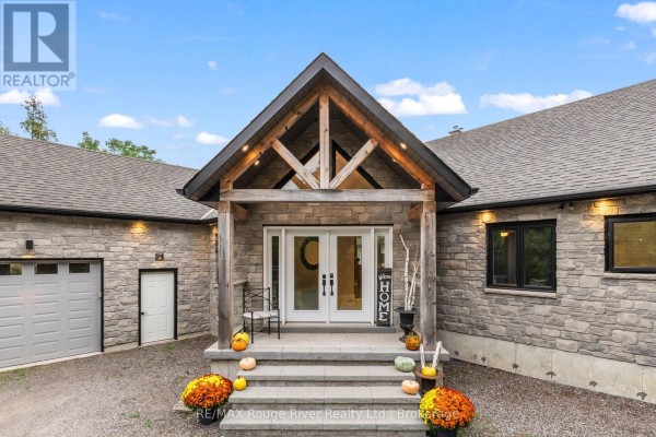 Close-up of the front entrance of a stone house, showing double doors, stone steps, and pumpkins. - 4500 Old Scugog Road, Clarington