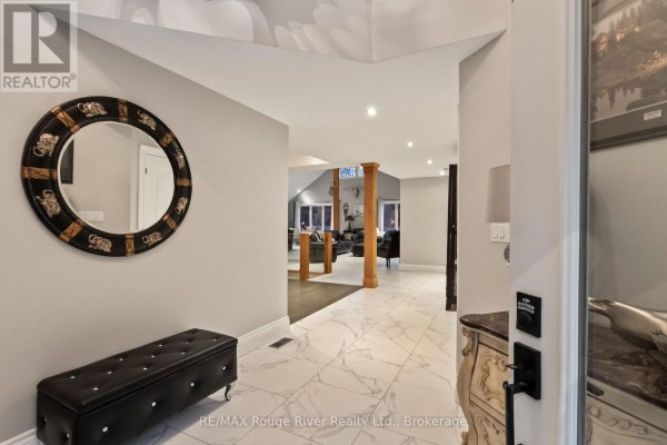 Interior view of a foyer with marble tile floors, a circular mirror, a bench, and an archway to the living area. - 4500 Old Scugog Road, Clarington