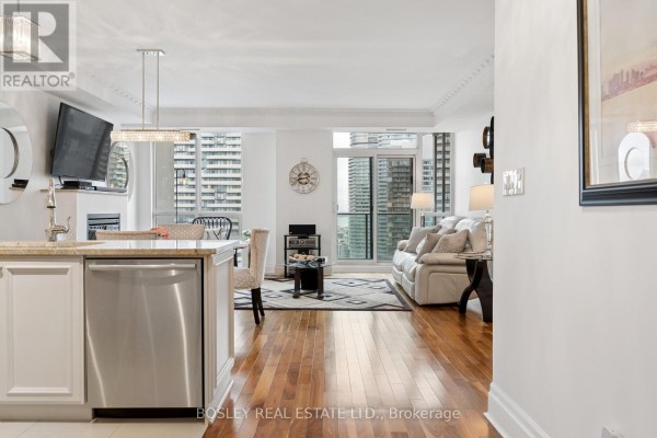 Open-concept living area with kitchen island, stainless steel dishwasher, and living room beyond. - 4501 - 16 Harbour Street, Toronto