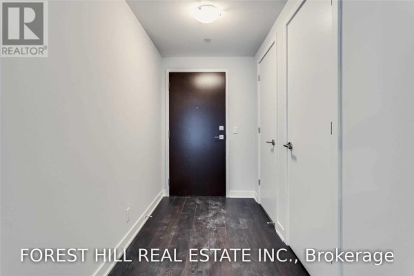 Entranceway of an apartment with a dark wood floor and white closets. - 4505 - 2221 Yonge Street, Toronto