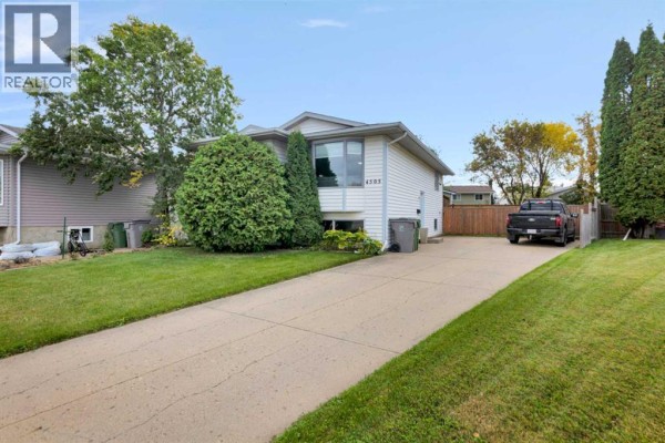Exterior of a light-colored house with a concrete driveway and green lawn. - 4505 30a Street Close, Lloydminster