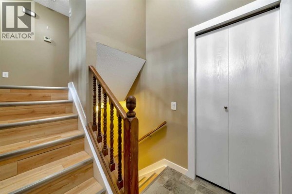 Interior staircase with light wood laminate treads, dark wood spindles, and textured wall. - 4505 30a Street Close, Lloydminster