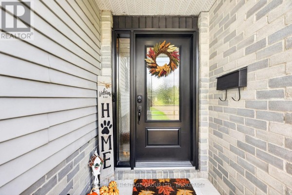Front door with glass panels and a fall wreath, surrounded by brick and siding. - 4505 Susan Drive, Elizabethtown Kitley