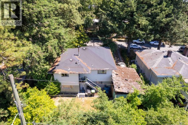 Close-up aerial view of the rear exterior of a house with a white staircase and surrounding greenery. - 4507 Todd Street, Vancouver