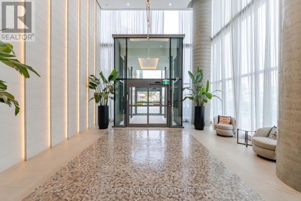 A bright, modern lobby with potted plants, glass elevators, and light-colored tiled flooring. - 4508 - 7890 Jane Street, Vaughan