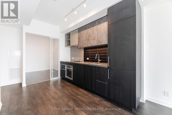 Contemporary kitchen with dark wood cabinets, stainless steel appliances, and grey tile backsplash. - 4508 - 7890 Jane Street, Vaughan