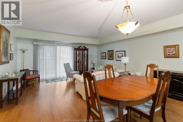 Living and dining room with wood floors, sofa, chairs, and dining table. - 451 Grand Marais Road West Unit# 114, Windsor