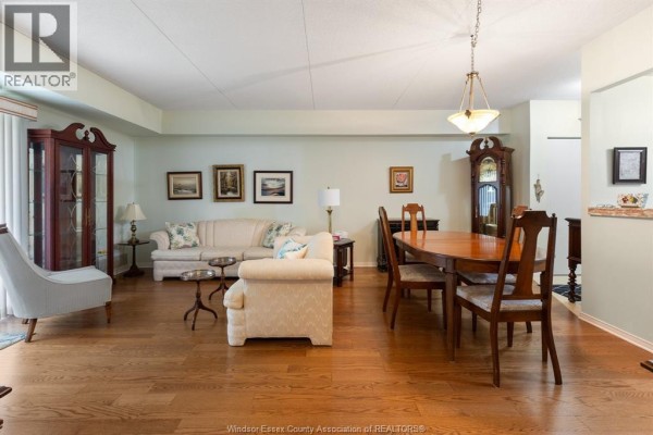 Living and dining area with wood floors, furniture, and a grandfather clock. - 451 Grand Marais Road West Unit# 114, Windsor