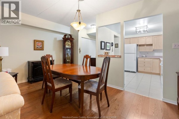 Dining area with view into a kitchen with light wood cabinets and white appliances. - 451 Grand Marais Road West Unit# 114, Windsor
