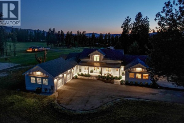 Night aerial view of the illuminated white farmhouse with a dark sky. - 4510-4520 Stewart Road E, Kelowna