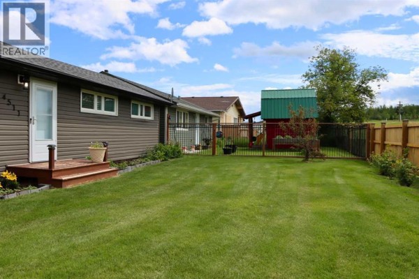 Backyard view of a fenced property with a green lawn and a small shed. - 4511 50 Avenue, Valleyview