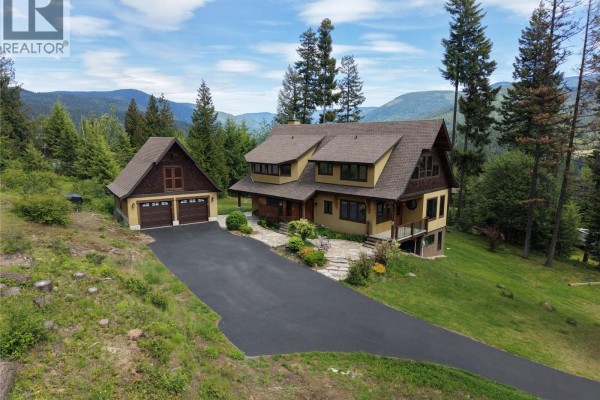 Exterior of a house with a wooden deck, large windows, and a sloped green lawn. - 4515 Beasley West Road, Nelson