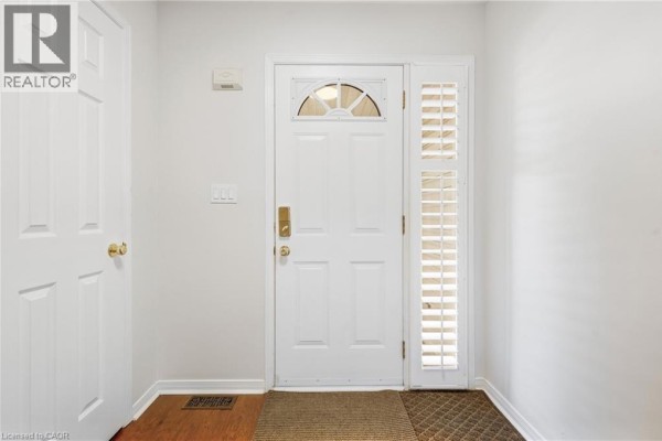 Interior view of a white front door with a sidelight window and two adjacent doors. - 4518 Garden Gate Terrace, Beamsville